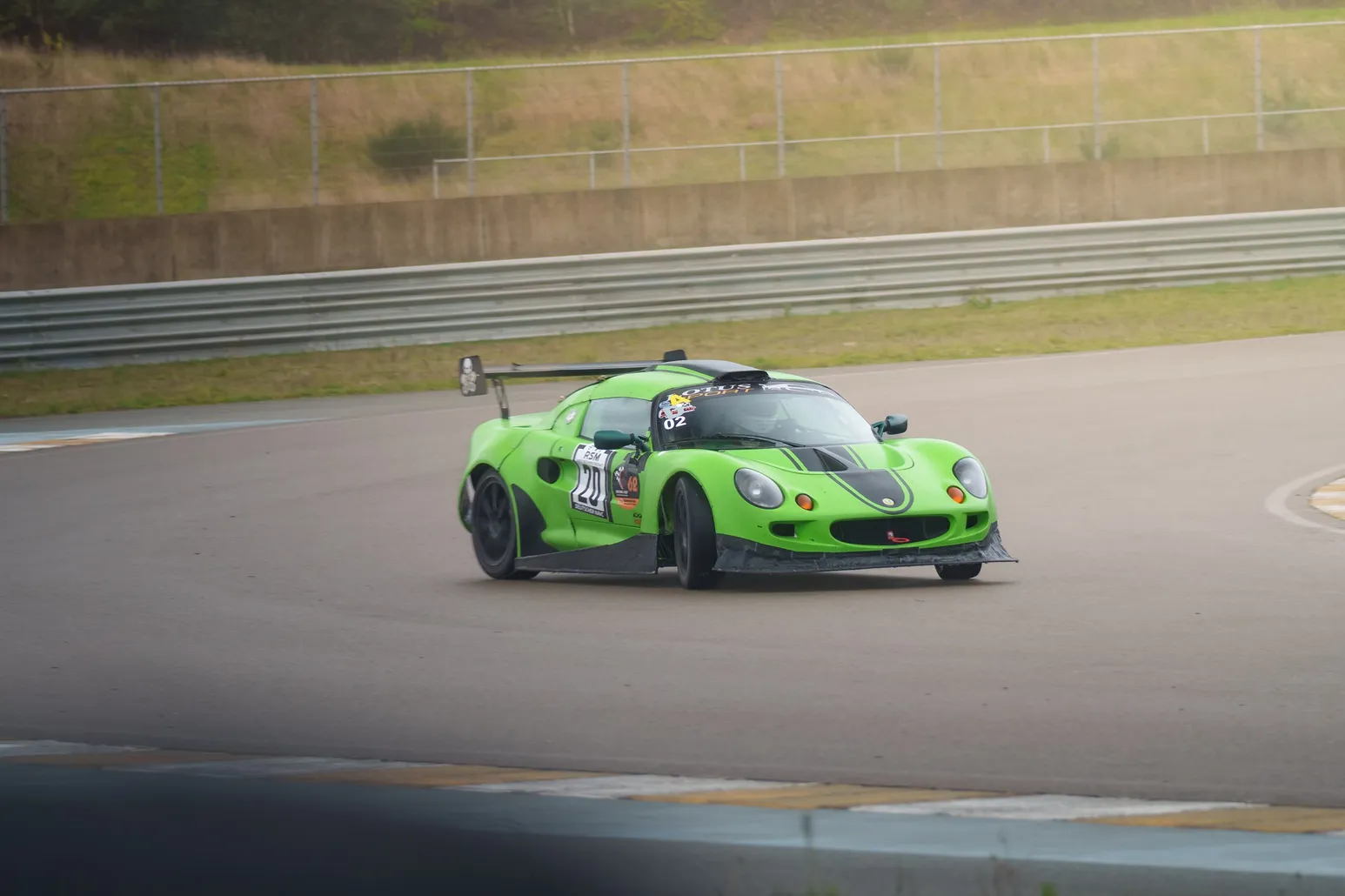 Green Lotus Elise turning in, blurred foreground