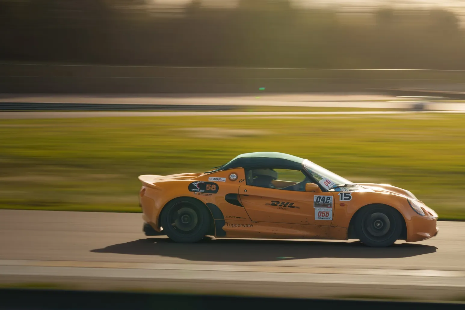 Orange Lotus Elise race car from the rear three-quarter