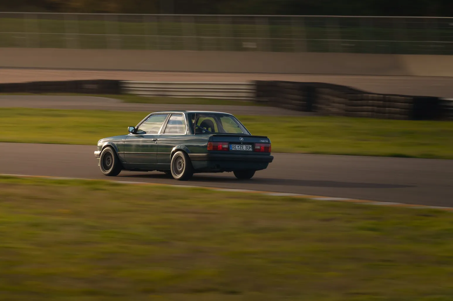 Dark green BMW E30 coupé in the evening light