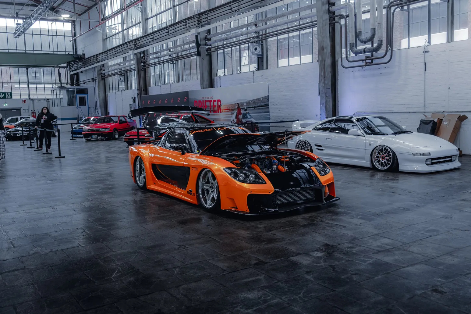 Orange widebody Mazda RX-7 in an industrial hall