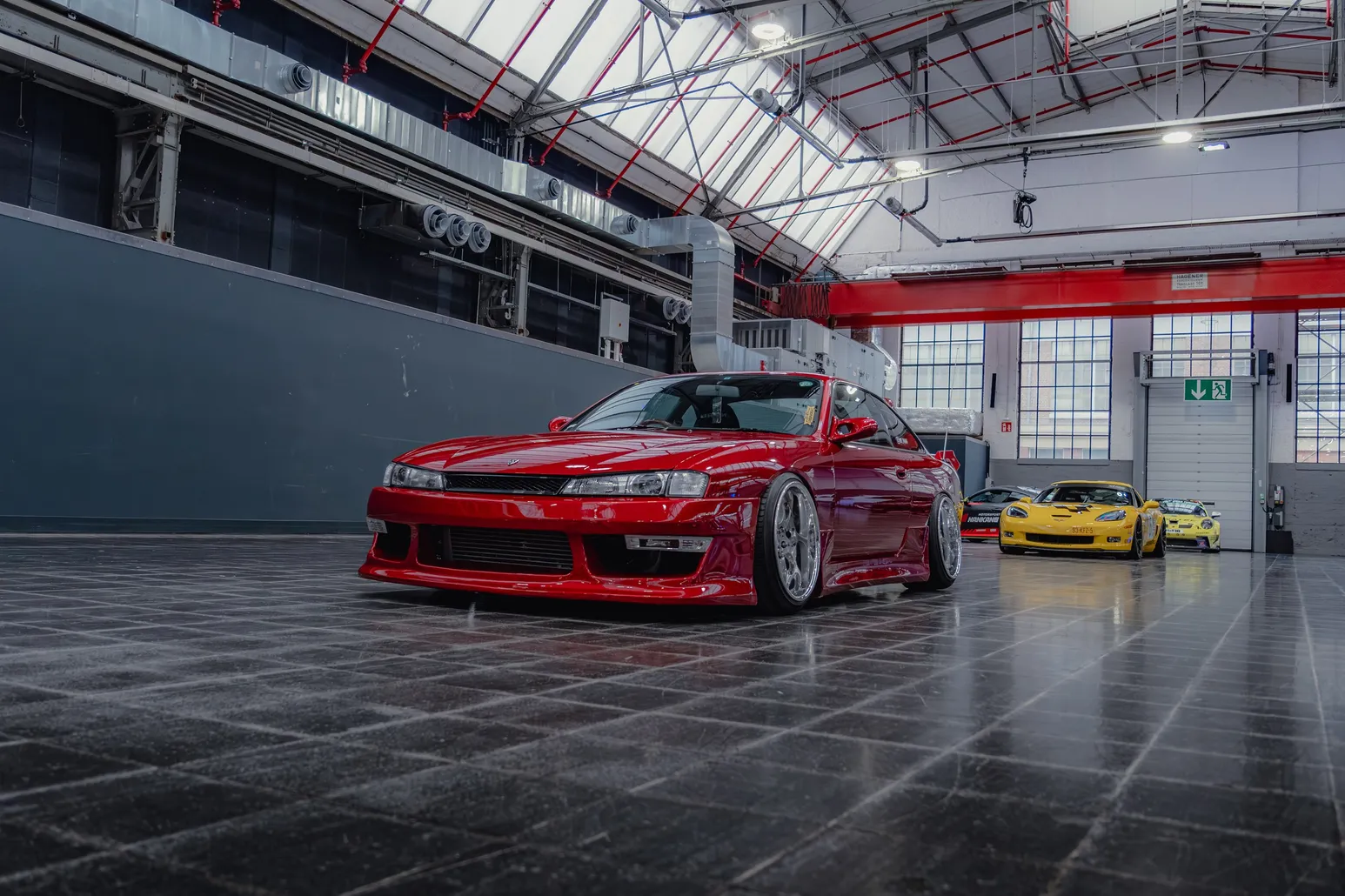Red Nissan Silvia S14 side view with yellow sports cars behind