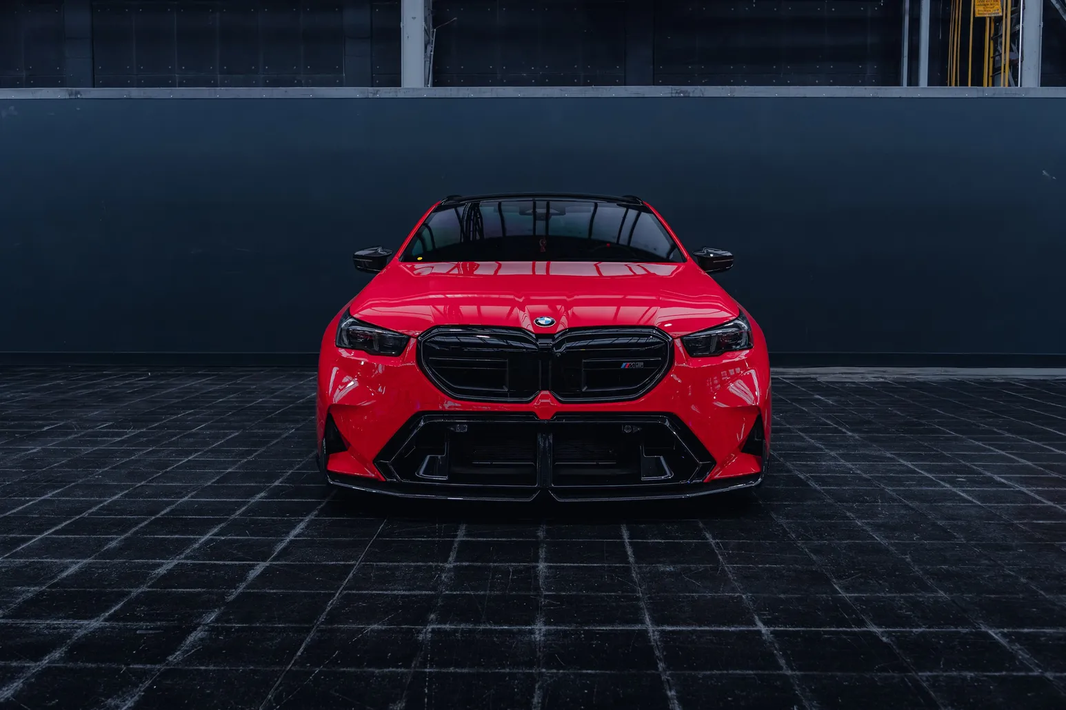 Red BMW head-on against a dark wall