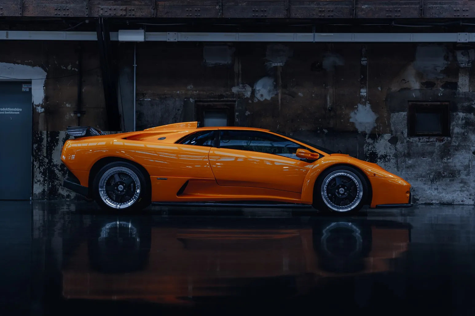 Orange Lamborghini Diablo side view against a dark wall