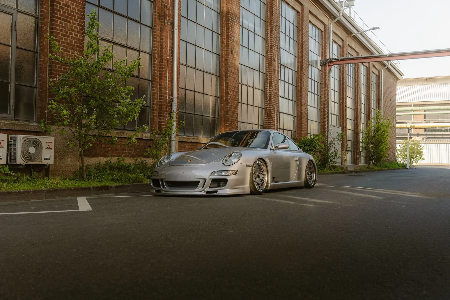 Silver Porsche 911 GT3 side view in front of the brick hall