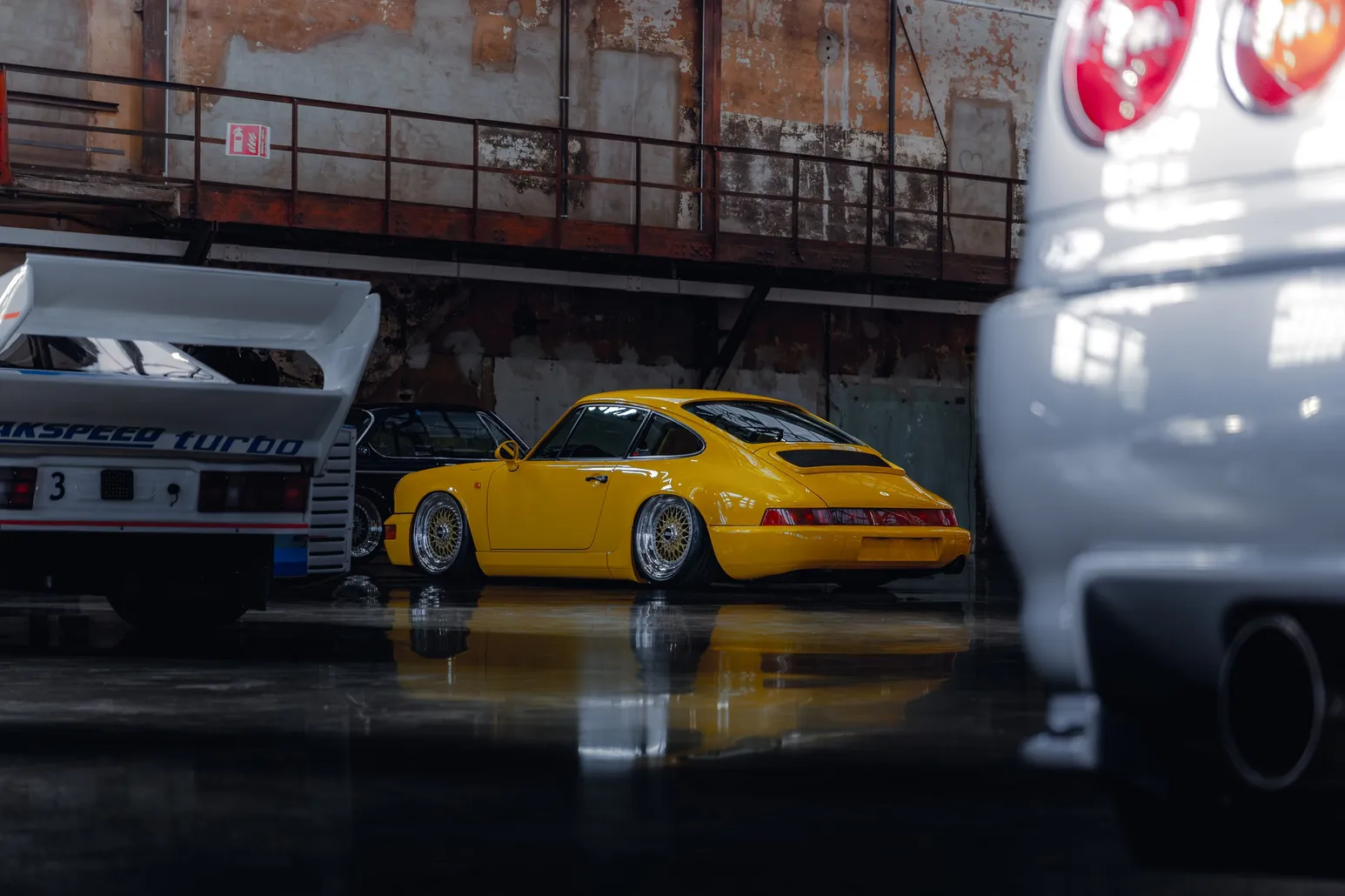 Yellow Porsche 964 framed by two blurred cars