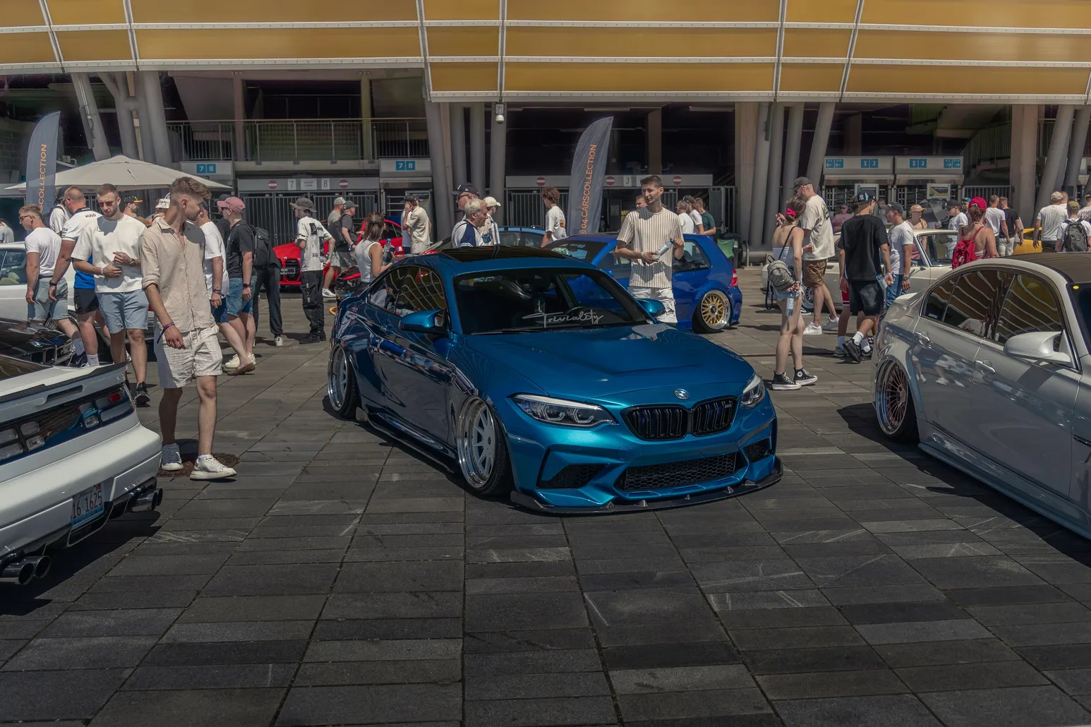 Blue BMW M2 in front of the stadium with a crowd