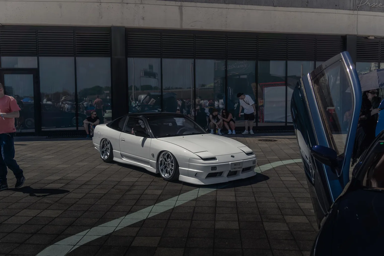 White Nissan 180SX convertible next to an open gullwing door