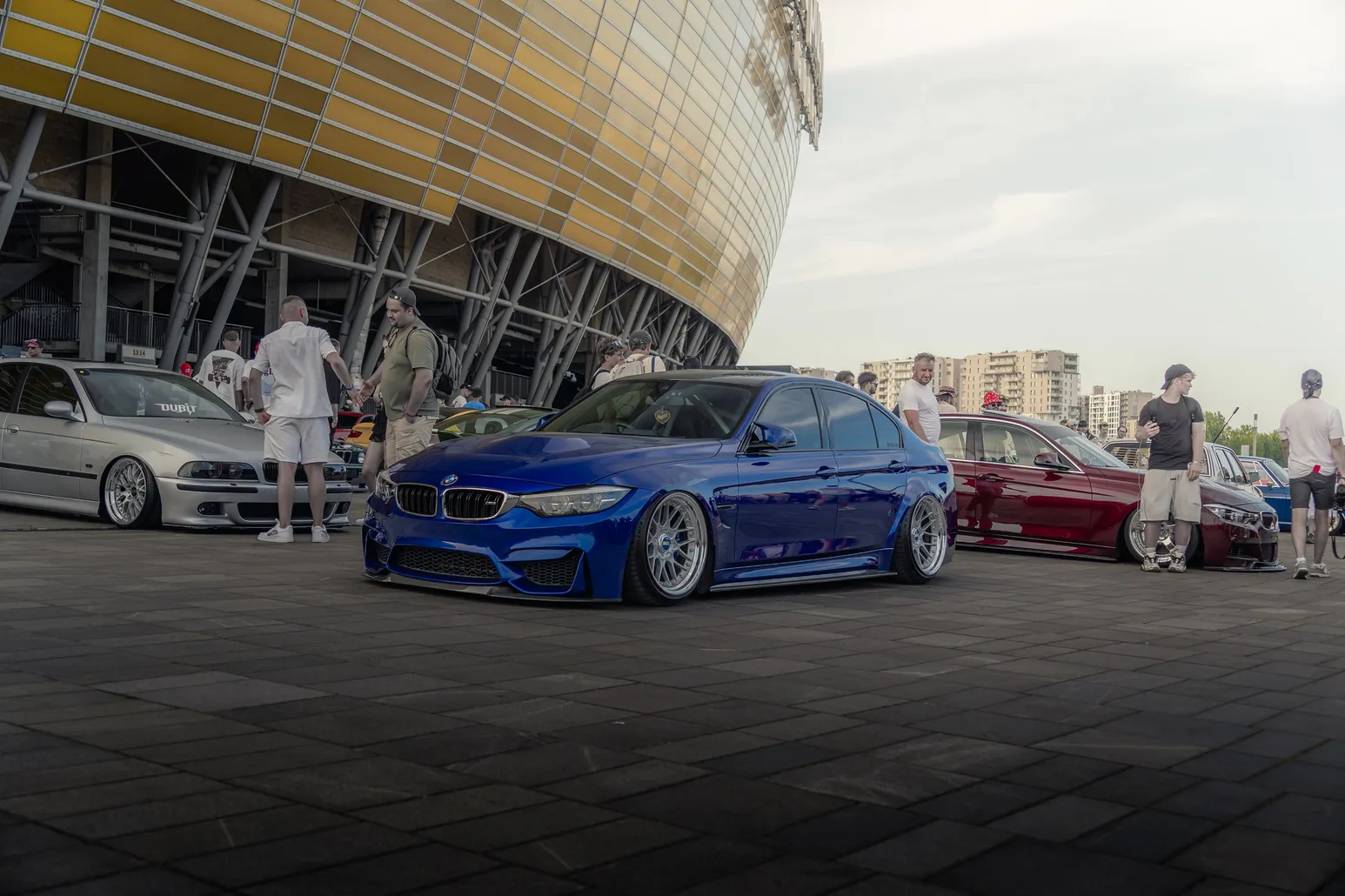 Blue BMW M3 in front of the golden stadium