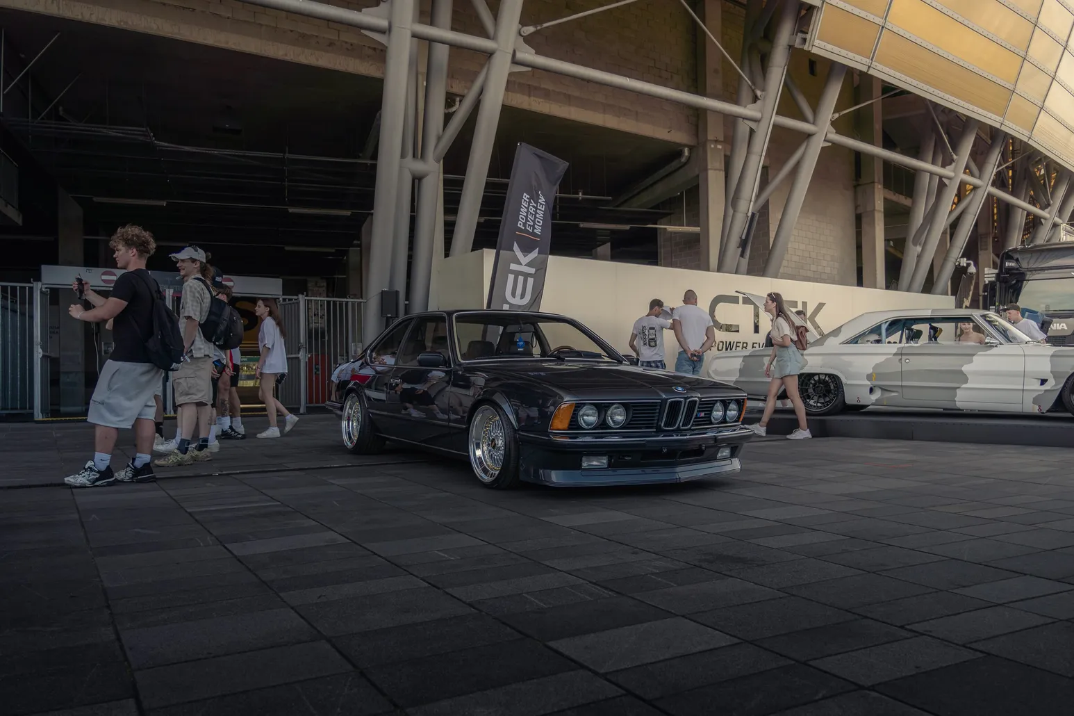 Black BMW E24 6 Series in front of the stadium
