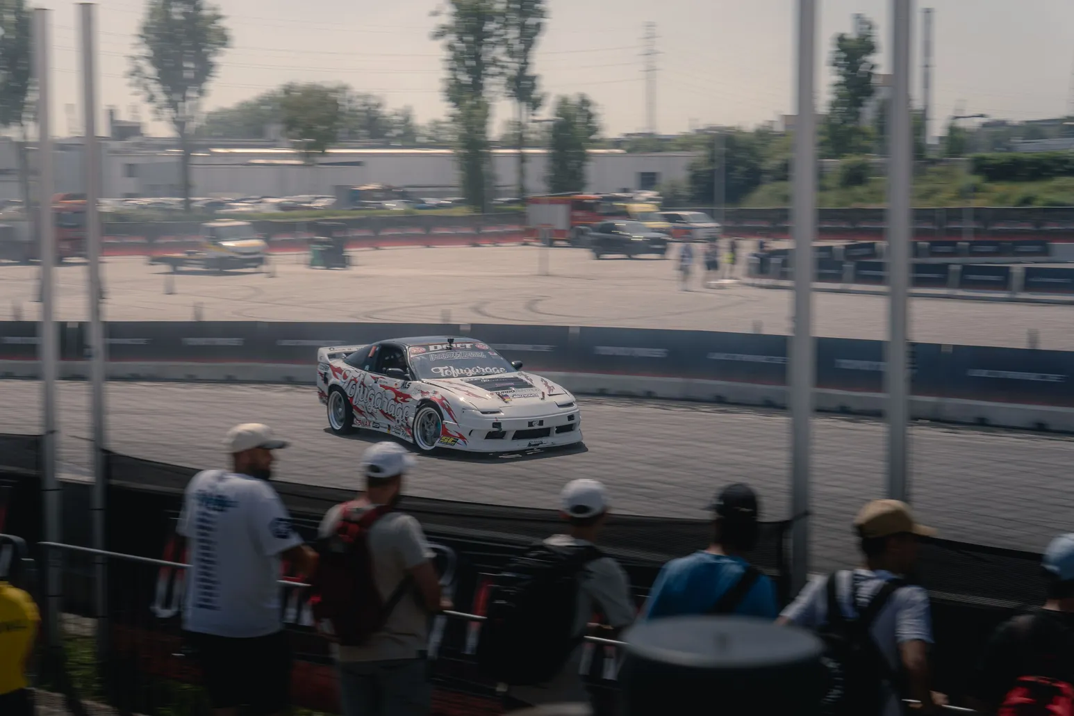 White drift car with race number in front of spectators