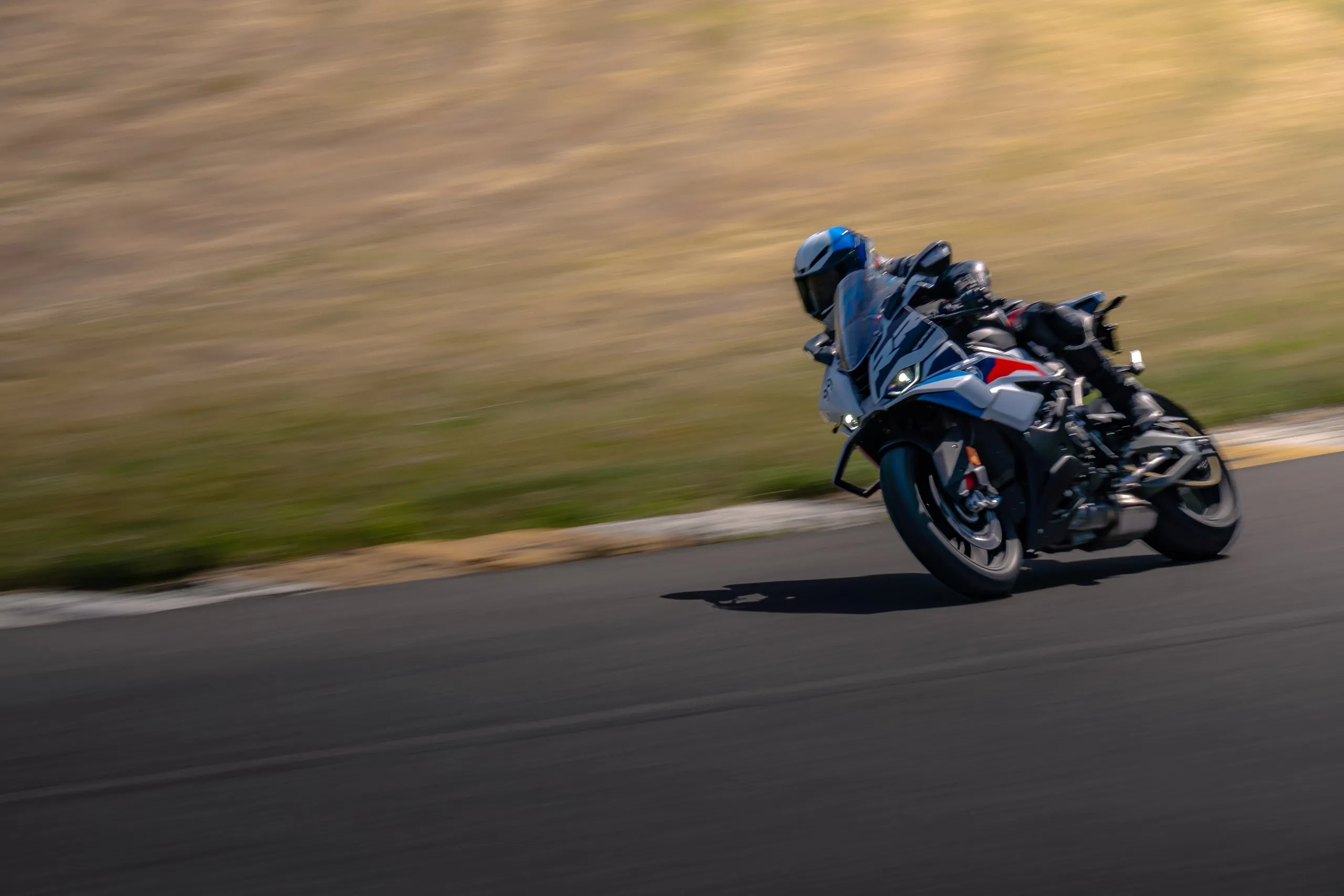 Rider in blue helmet at full lean, motion-blurred background