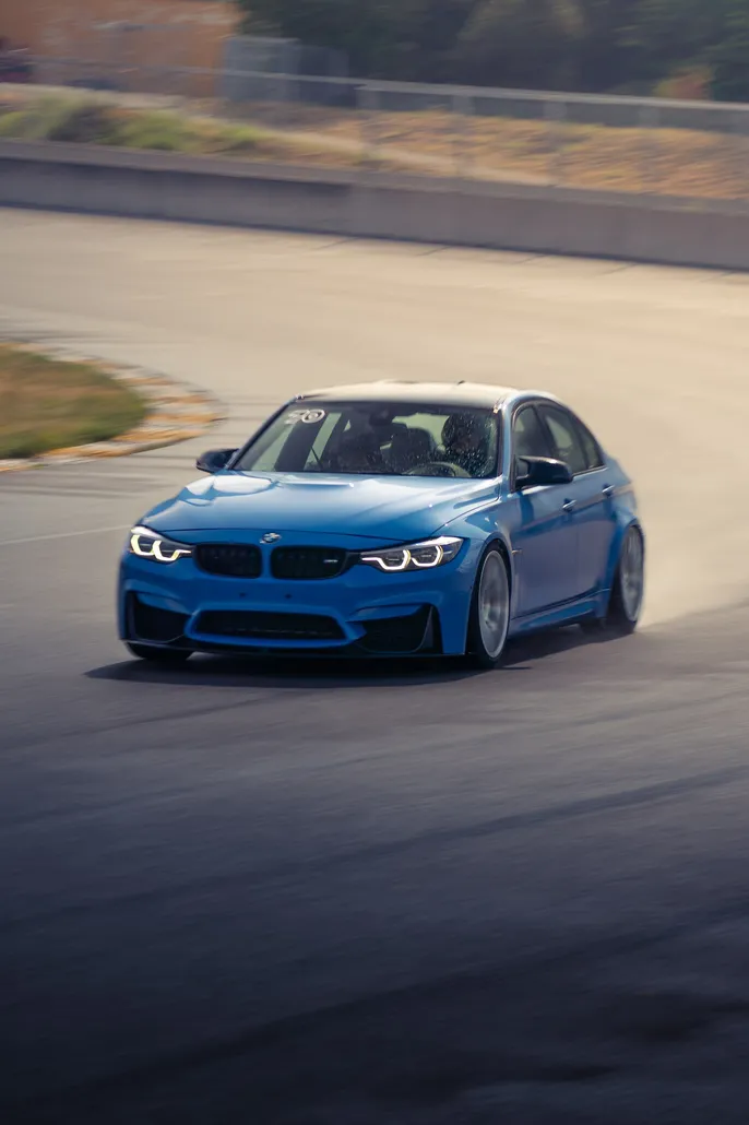 Blue BMW M3 front view drifting on a wet corner