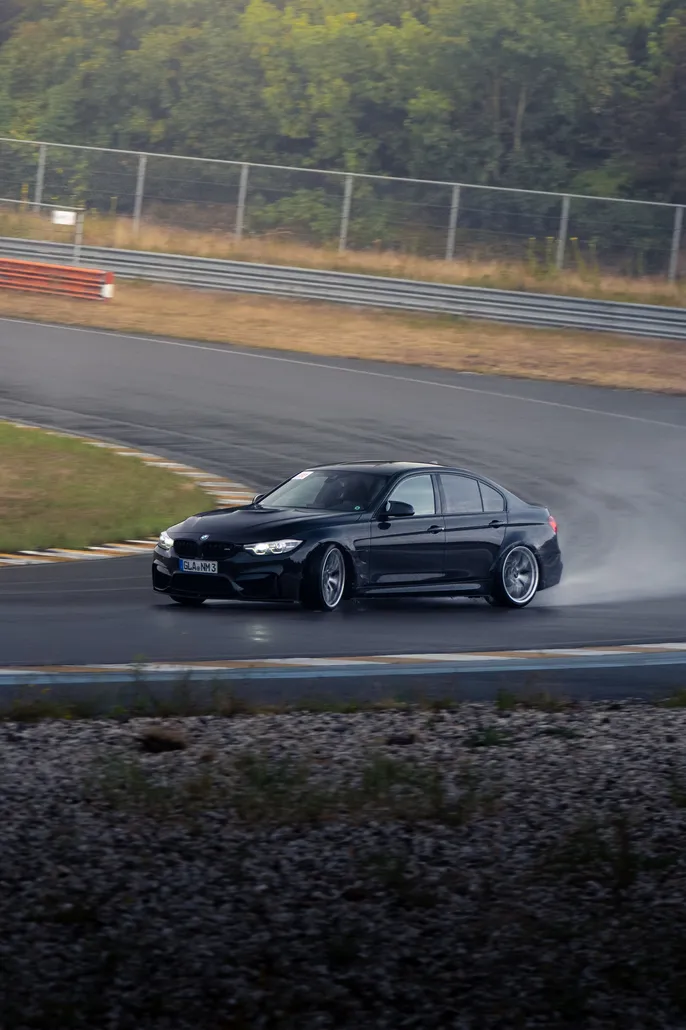 Black BMW M3 drifting through the corner with spray