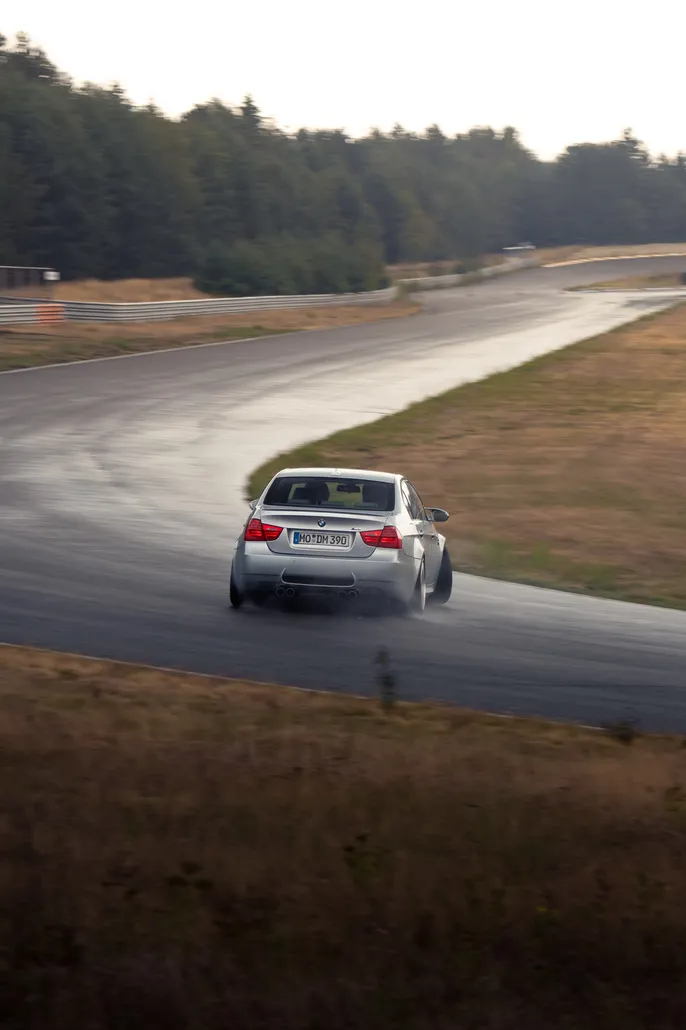 White BMW drifting on a winding wet section
