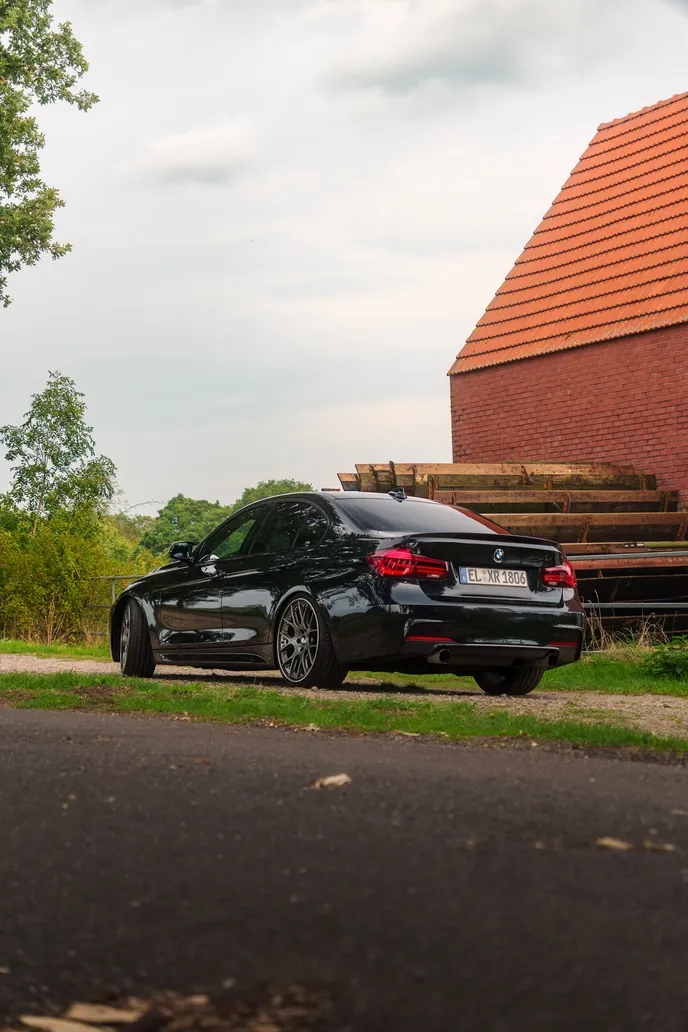 Black BMW F30 rear in front of a red brick barn