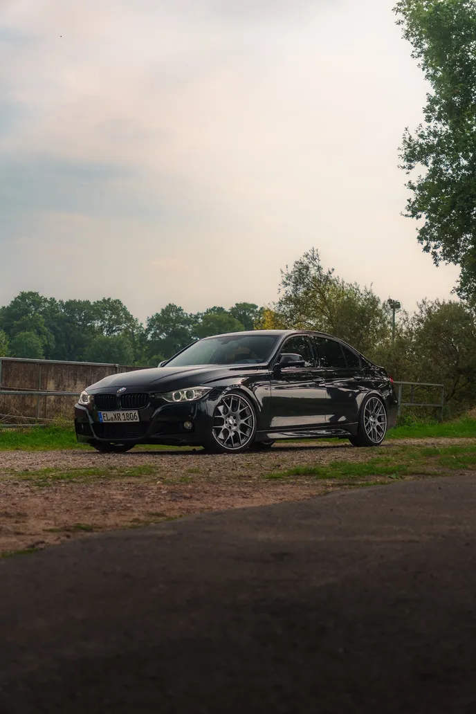 Black BMW F30 by the river, portrait format