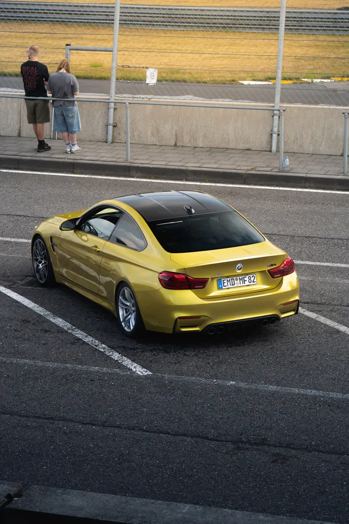 Yellow BMW M4 in the paddock with spectators behind
