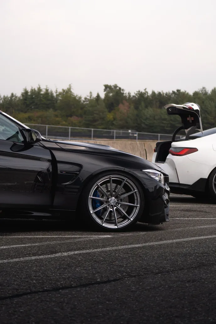 Rear of a black BMW with a white car beside, portrait format