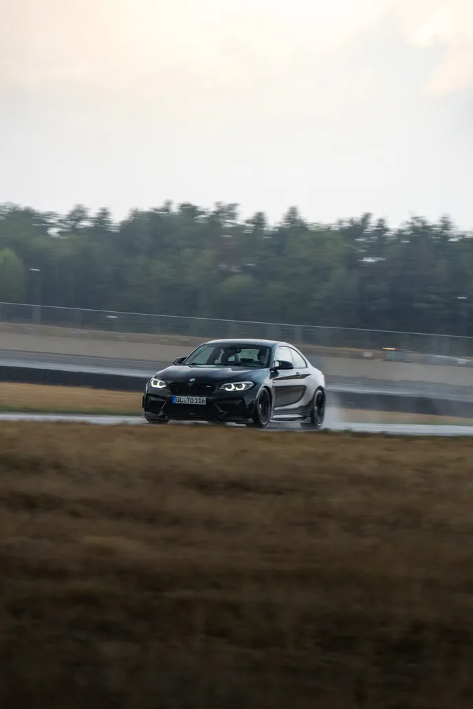 Dark BMW drifting in front of the tree line, portrait format