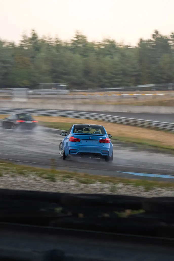 Blue BMW M3 drifting on the wet track, portrait format