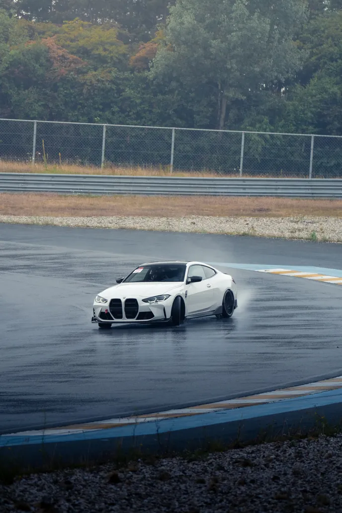 White BMW M4 drifting on the wet corner, portrait format