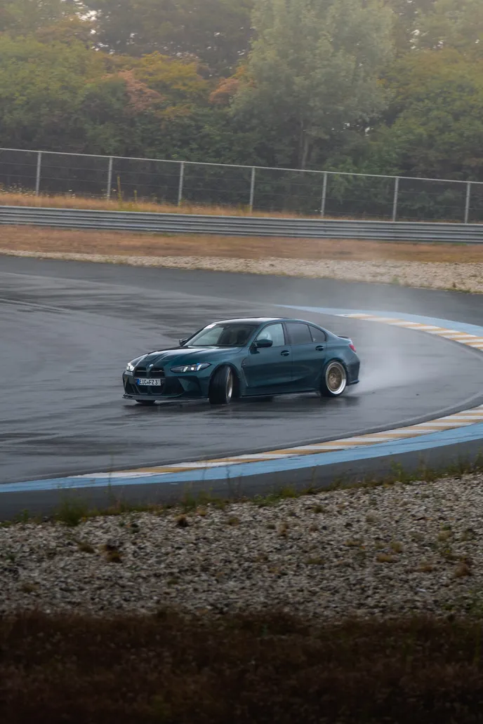 Green BMW M3 sliding over the kerb, portrait format