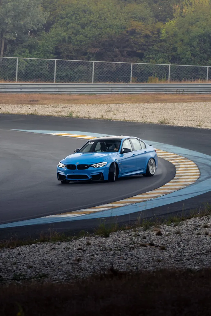 Blue BMW M3 drifting over the blue kerb