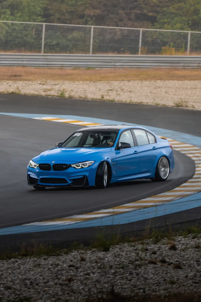 Blue BMW M3 front three-quarter at full lock
