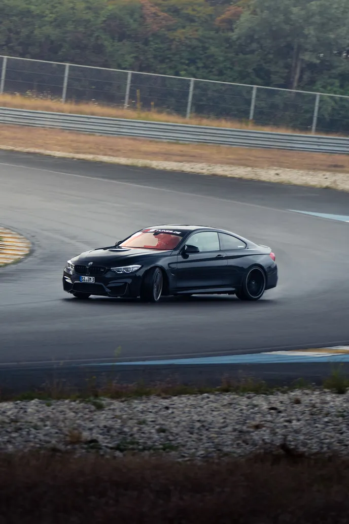 Black BMW M4 sliding over the kerb