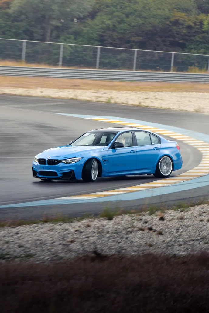 Blue BMW M3 drifting with smoke over the kerb