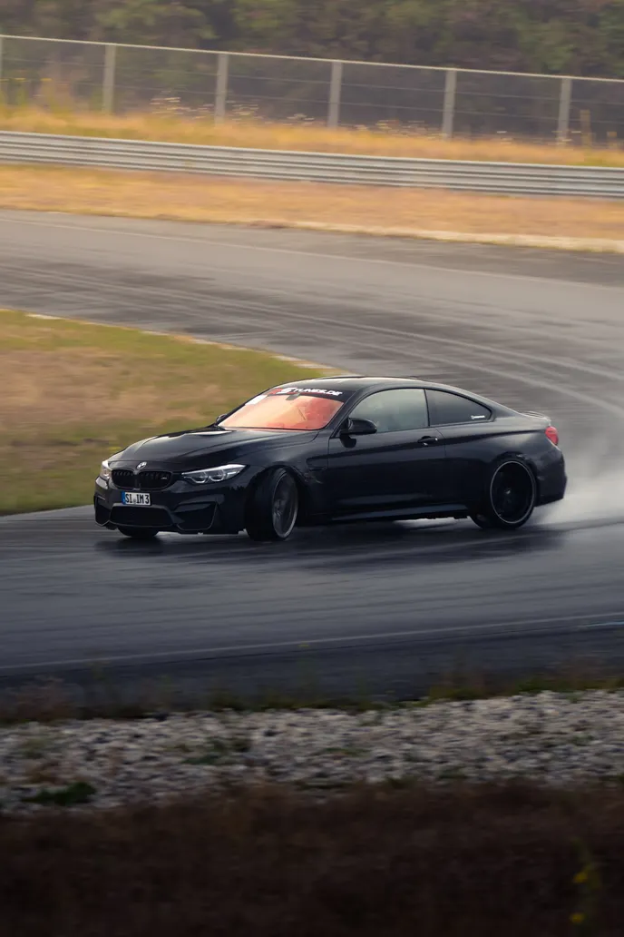 Black BMW M4 sliding through a wet corner