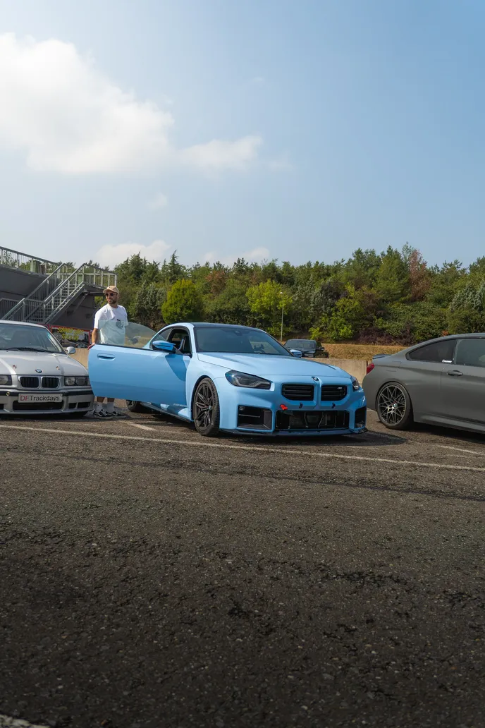 Blue BMW M2 with its driver in the paddock