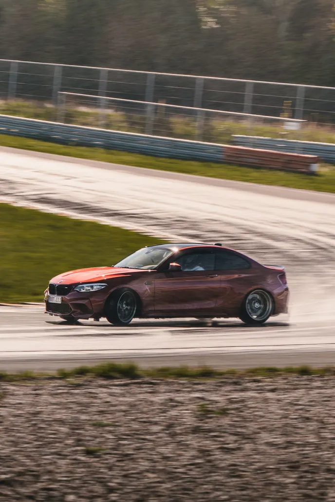 Roter BMW M2 rutscht mit Rauch, Hochformat