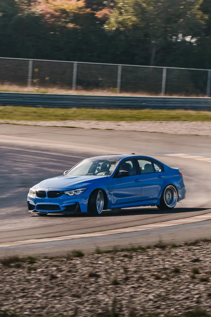 Blauer BMW M3 driftet im Infield, Hochformat