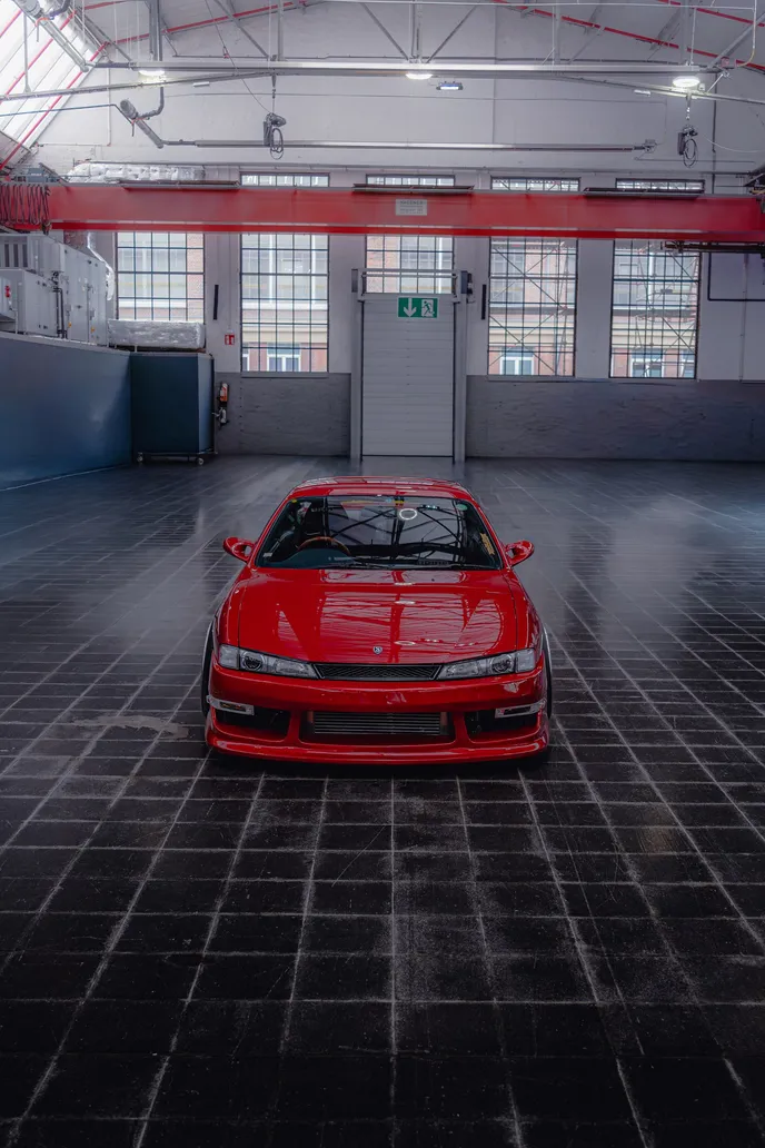 Red Nissan Silvia head-on on a tiled floor, portrait format