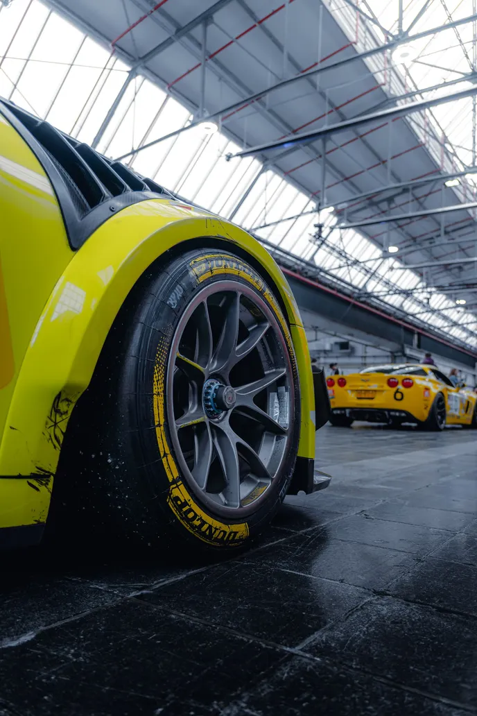 Yellow rear wheel of a widebody Porsche from a low angle, portrait format