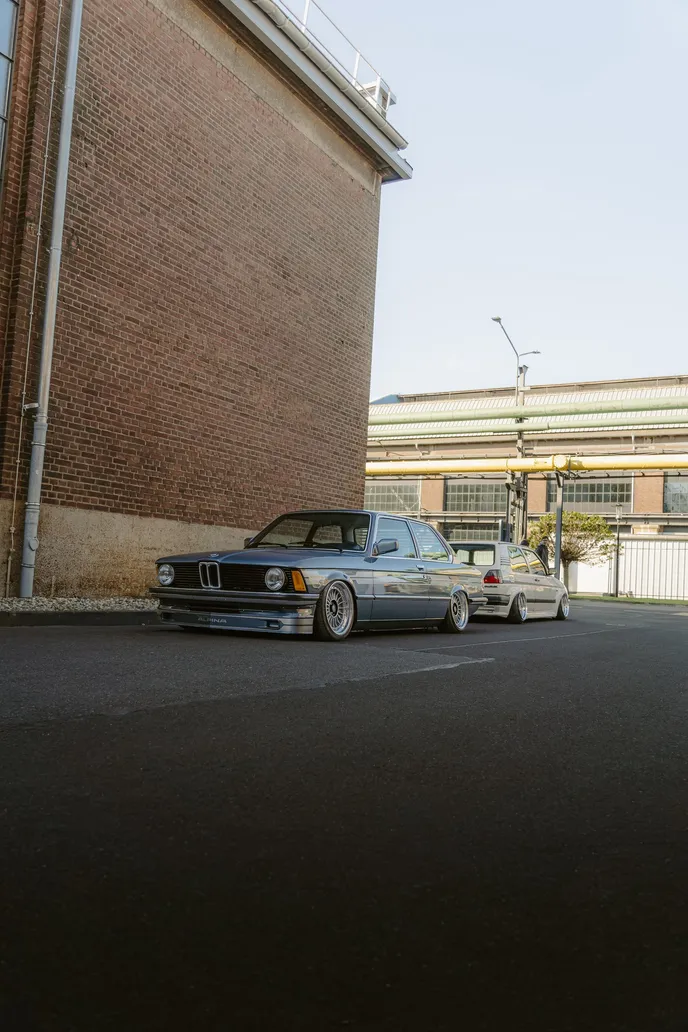 Silver BMW E21 between industrial buildings, portrait format