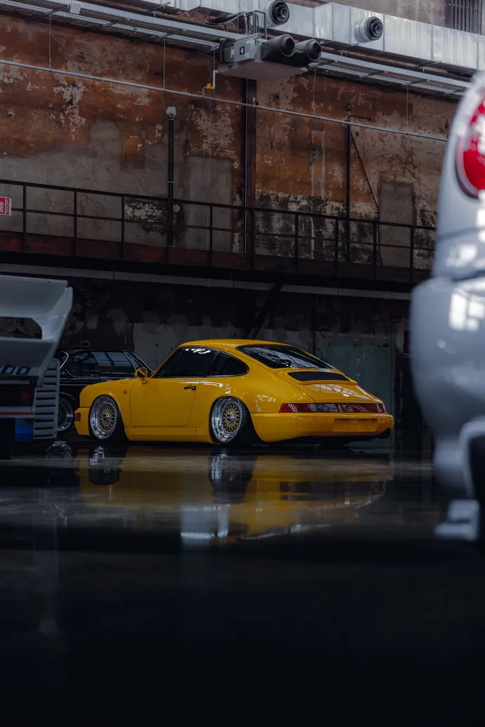 Yellow Porsche 911 (964) between other cars, portrait format