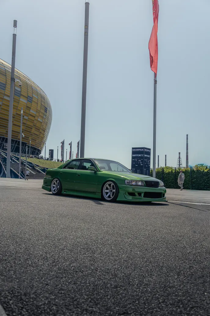 Green Toyota Chaser with stadium and flagpoles, portrait format