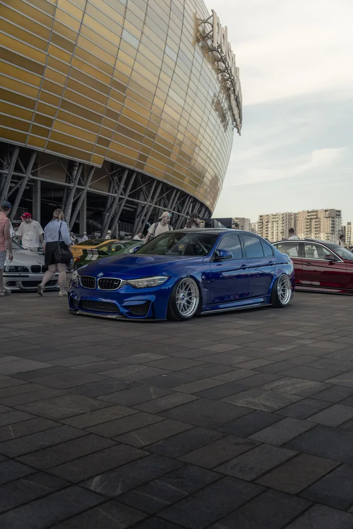 Blue BMW M3 with the stadium behind, portrait format