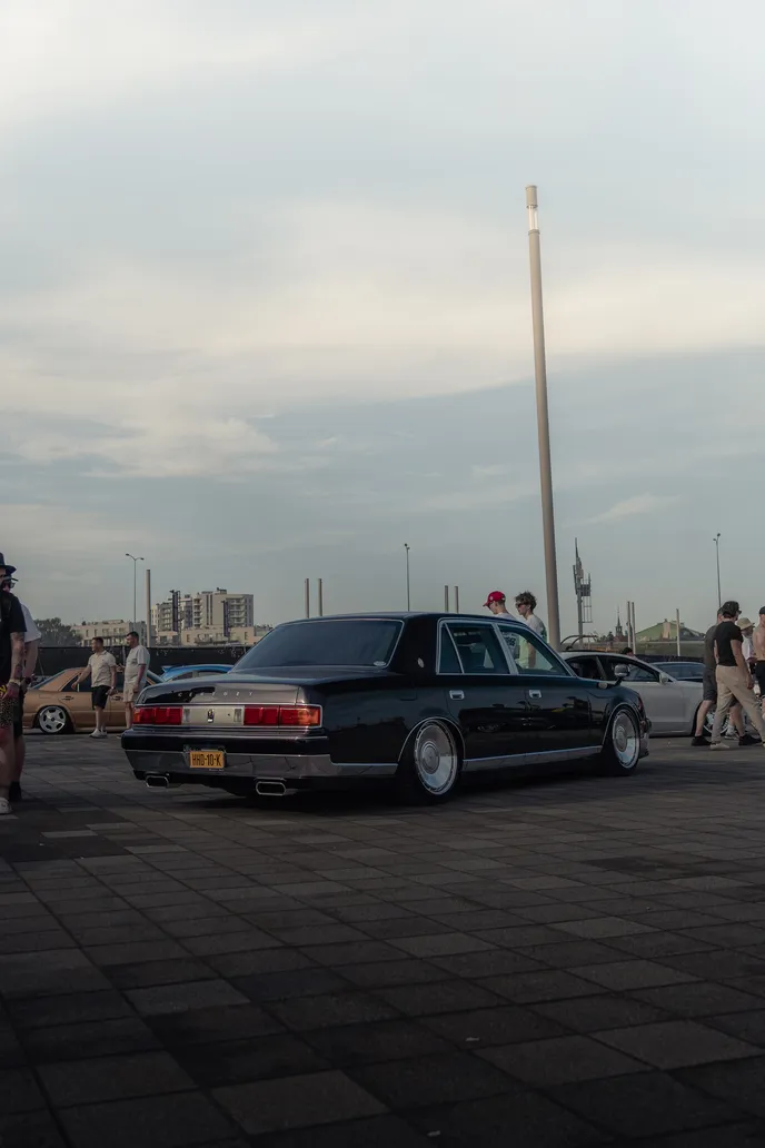 Black sedan under a wide sky, portrait format