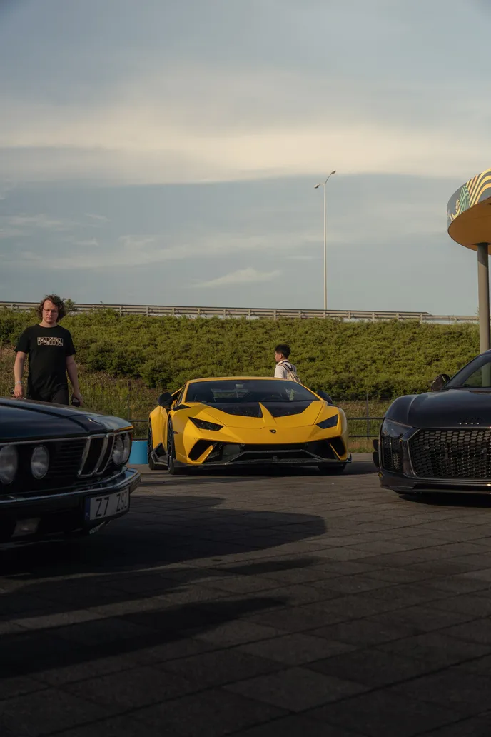 Yellow Lamborghini between parked cars, portrait format
